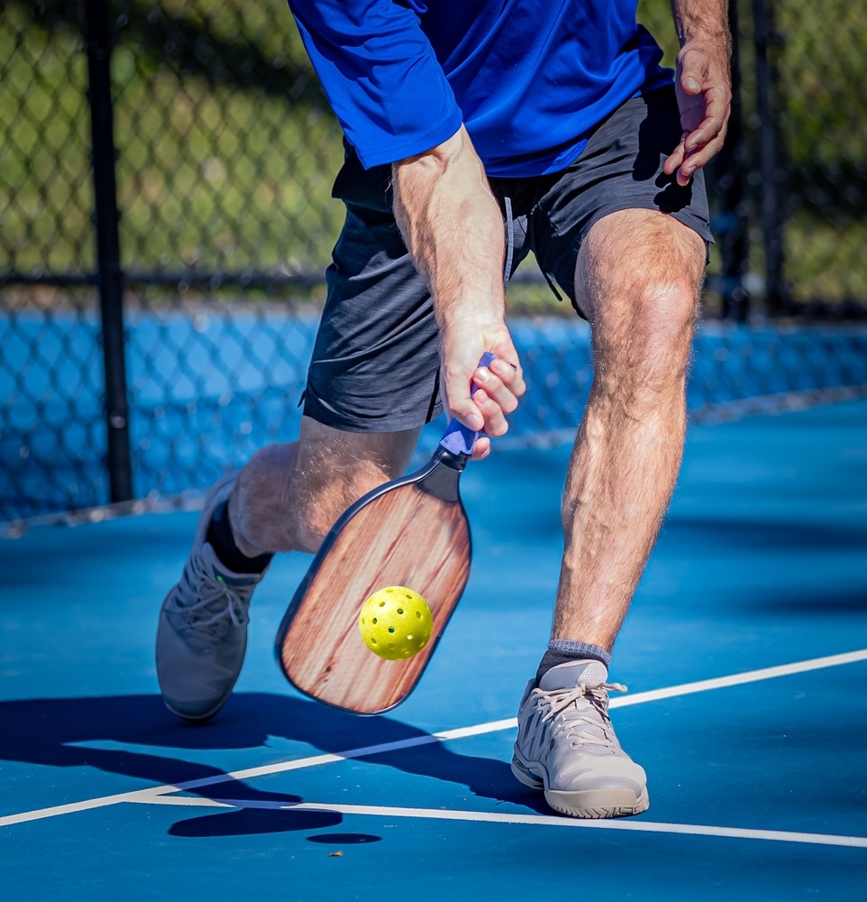 A lower view of a person serving a pickleball shot