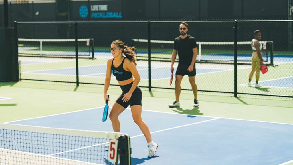 a girl is playing pickleball game in the court along with the other players