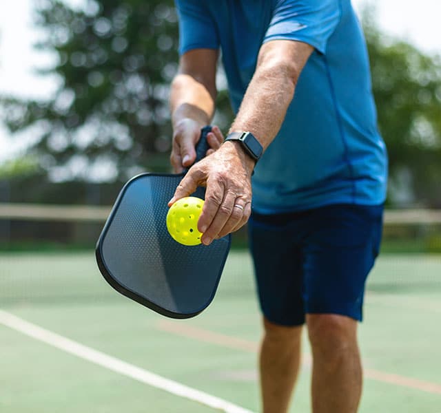 a person is all set to strike the pickleball in court