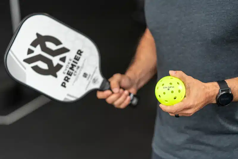 A view of a person holding a paddle and pickleball