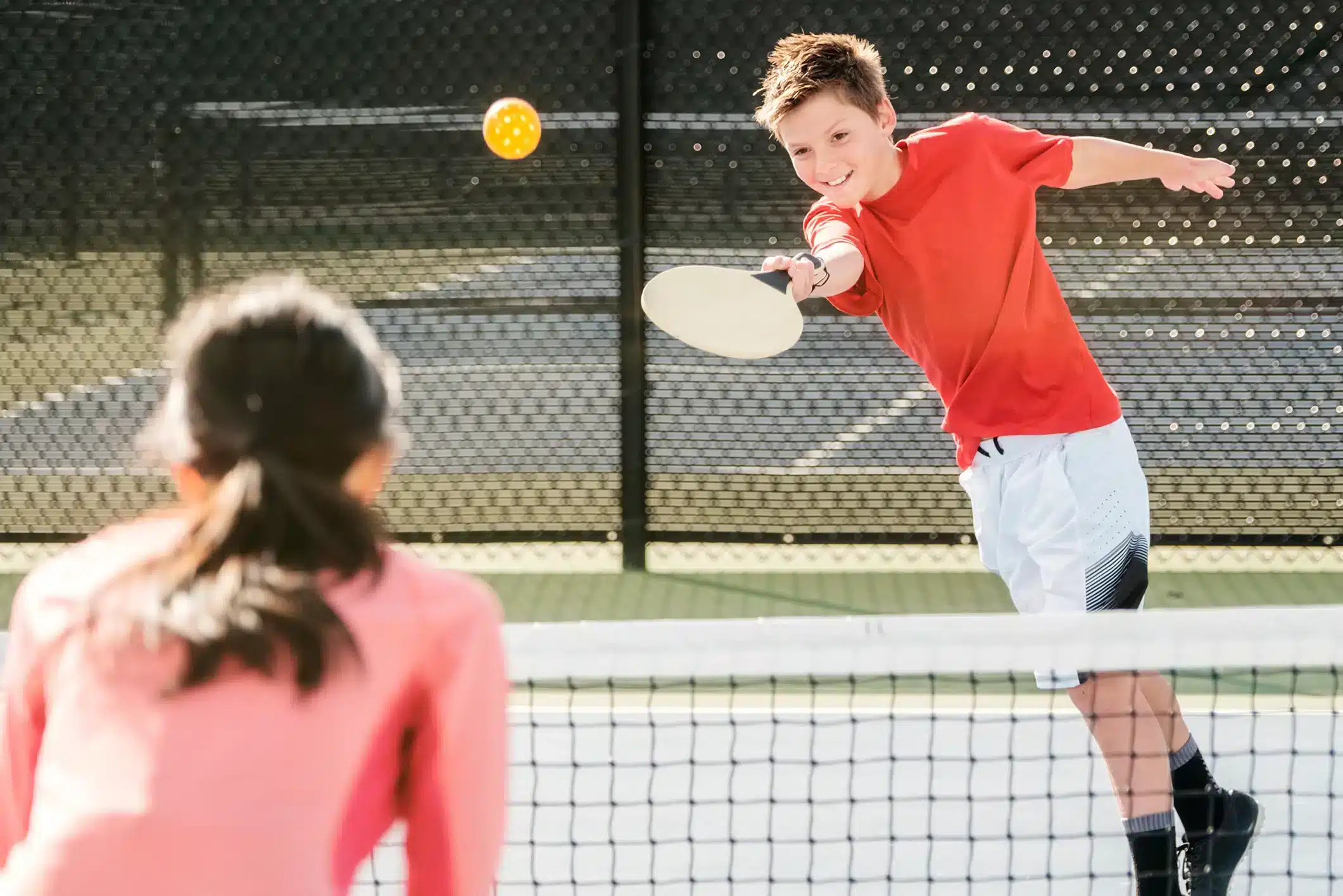 A view of a kid hitting a pickleball