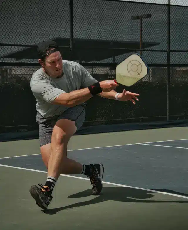 A view of a person holding a paddle and hitting a pickleball shot