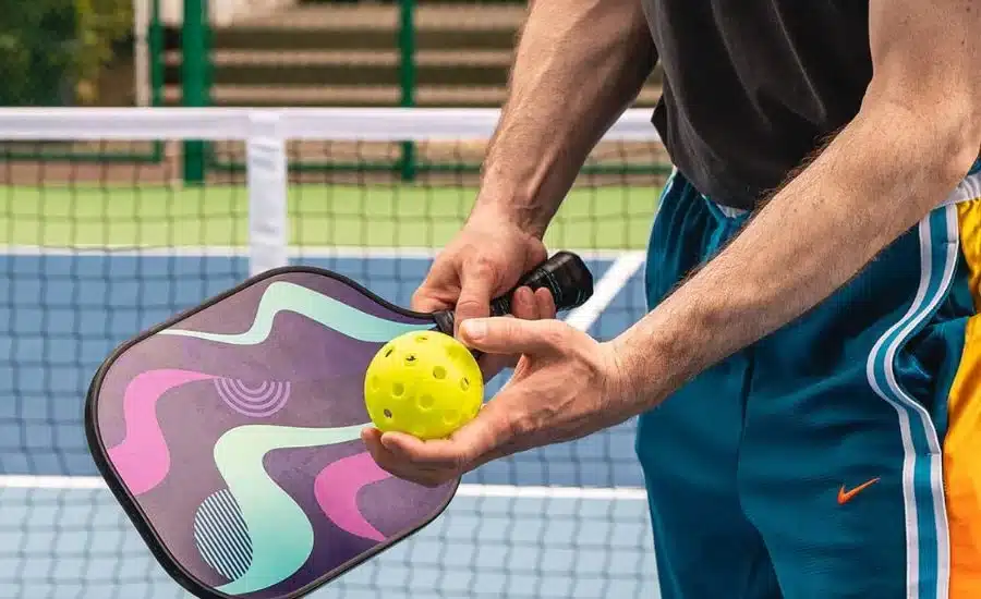 A view of a person holding a paddle and pickleball