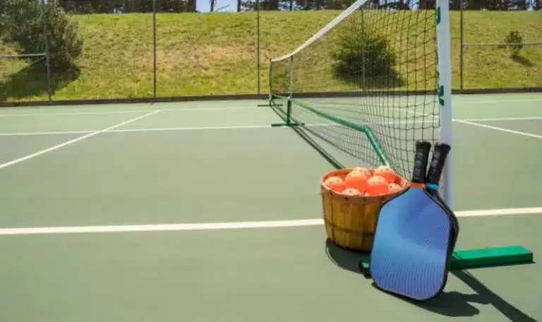 A view of a pickleball court with balls and paddle next to the net