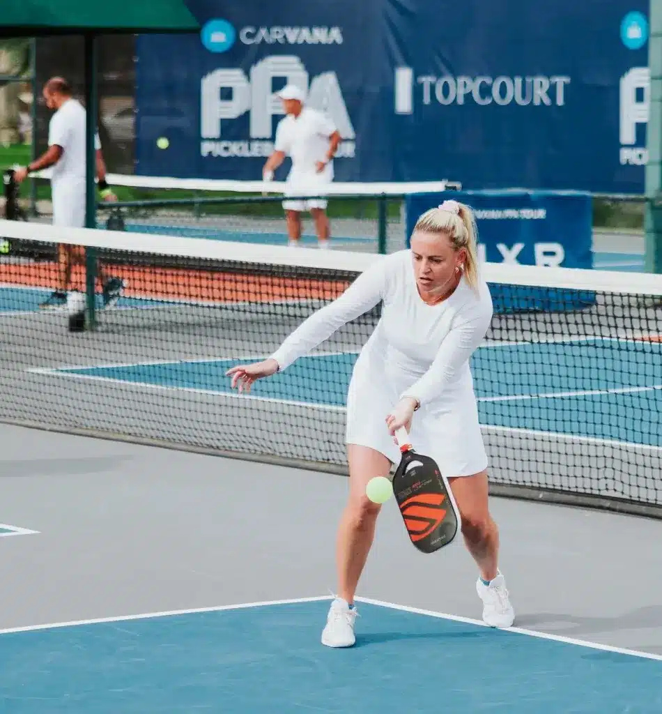 A view of a woman hitting a pickleball shot on a court