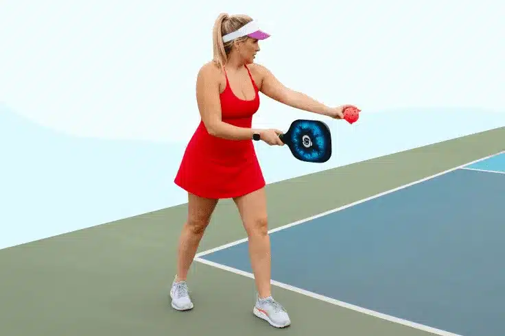 A view of a woman in red serving in pickleball