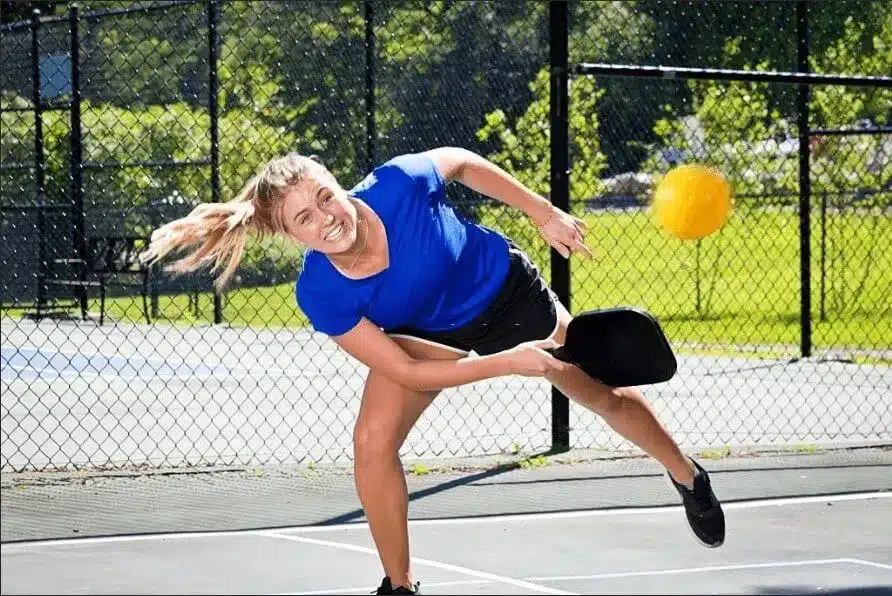 A woman in blue hitting a deep return serve pickleball shot