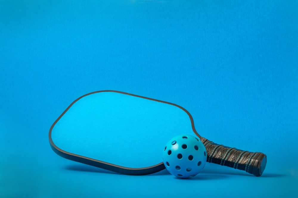 A view of a blue pickleball paddle and a ball