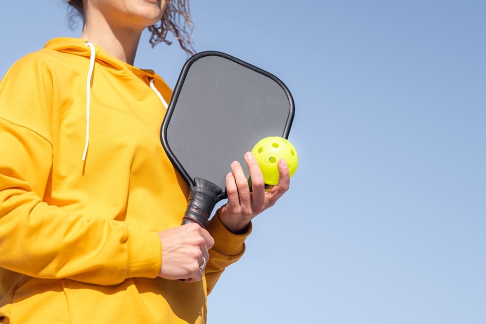 A view of a person holding a ball and a pickleball paddle with overgrip