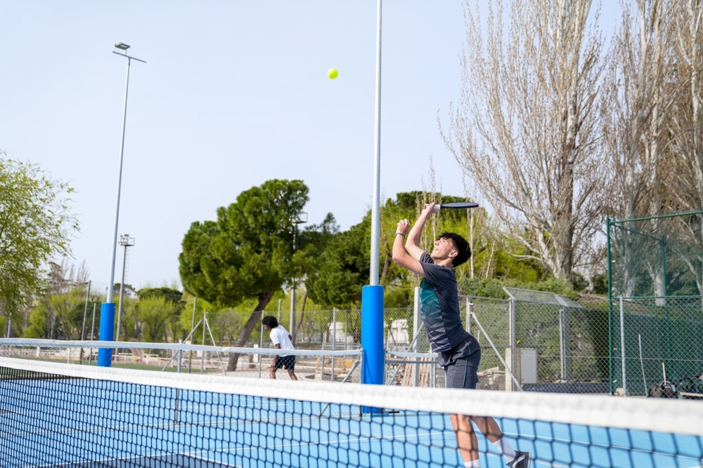 A view of a guy hitting a pickleball overhead smash