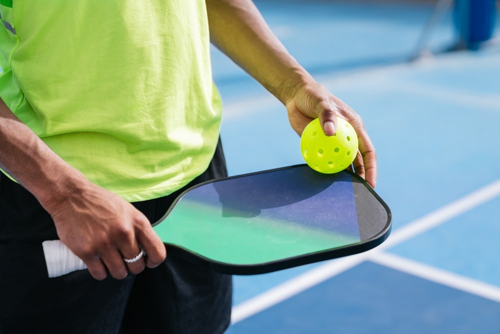 A view of a person holding a pickleball paddle with a ball